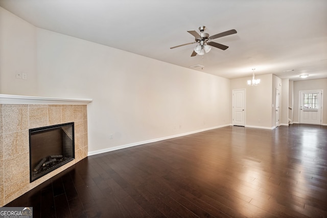 249 Madison Ave, Acworth, GA 30102 - unfurnished living room featuring visible vents, baseboards, a tiled fireplace, dark wood-style flooring, and ceiling fan with notable chandelier
