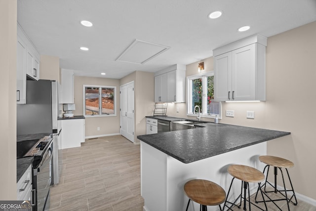 1190 Plantation Dr, Villa Rica, GA 30180 - kitchen featuring dark countertops, a breakfast bar, a peninsula, stainless steel appliances, and a sink