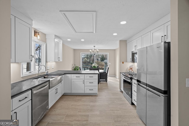 1190 Plantation Dr, Villa Rica, GA 30180 - kitchen featuring dark countertops, appliances with stainless steel finishes, a peninsula, white cabinets, and a sink