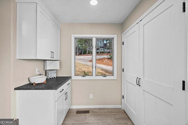 1190 Plantation Dr, Villa Rica, GA 30180 - kitchen with visible vents, baseboards, dark countertops, and white cabinets