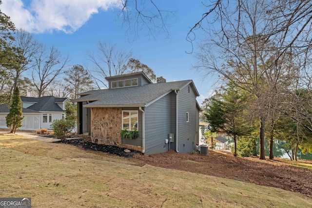 1190 Plantation Dr, Villa Rica, GA 30180 - view of front of property featuring a front yard, cooling unit, a chimney, a shingled roof, and stone siding