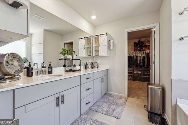 full bath featuring visible vents, a washtub, double vanity, tile patterned floors, and a sink