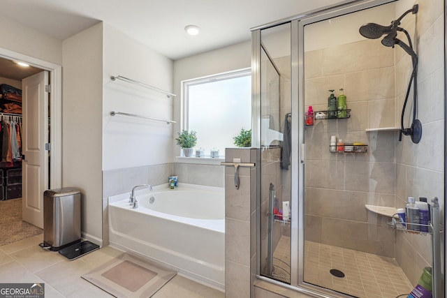 bathroom with tile patterned flooring, a shower stall, a walk in closet, and a bath