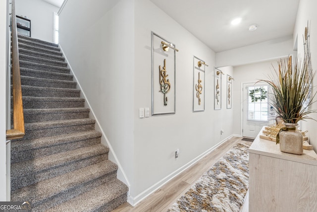 stairway with wood finished floors and baseboards