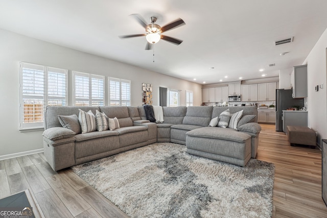 living room with visible vents, baseboards, ceiling fan, light wood-type flooring, and recessed lighting