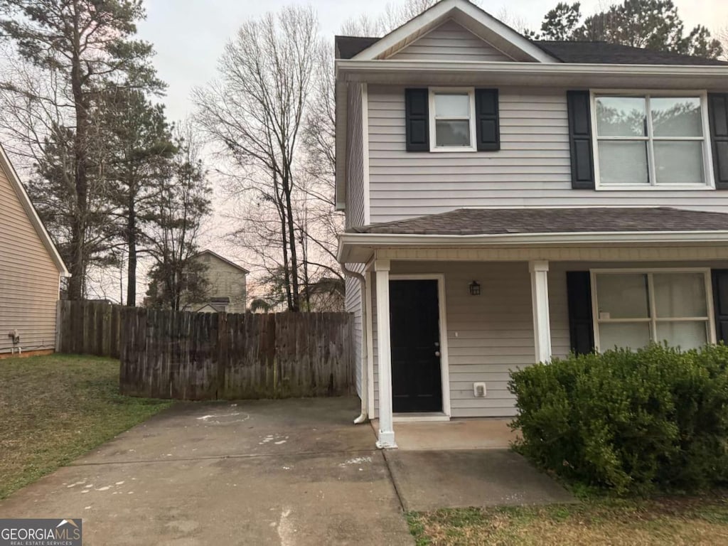 view of front of home featuring fence, covered porch, and roof with shingles