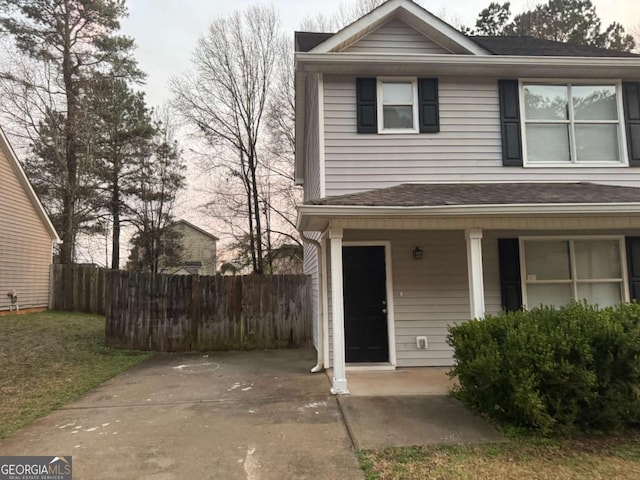 view of front of home featuring fence, covered porch, and roof with shingles