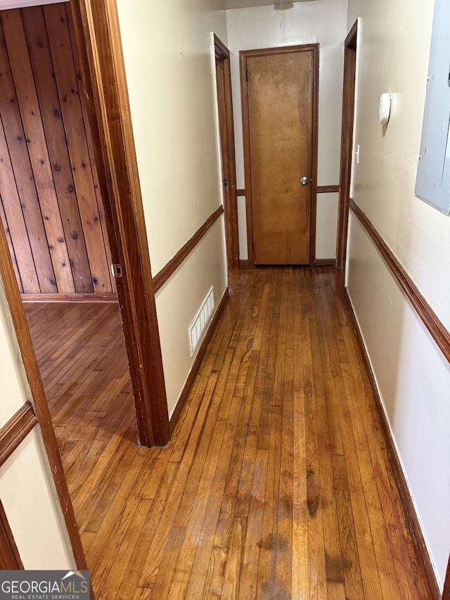 hall featuring electric panel, visible vents, baseboards, and hardwood / wood-style flooring