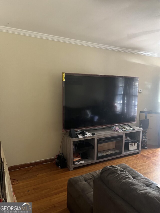 living room with baseboards, wood finished floors, and crown molding