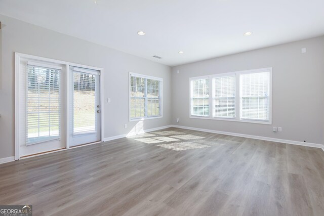 unfurnished living room with recessed lighting, light wood-type flooring, and baseboards
