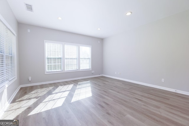 empty room featuring recessed lighting, wood finished floors, visible vents, and baseboards