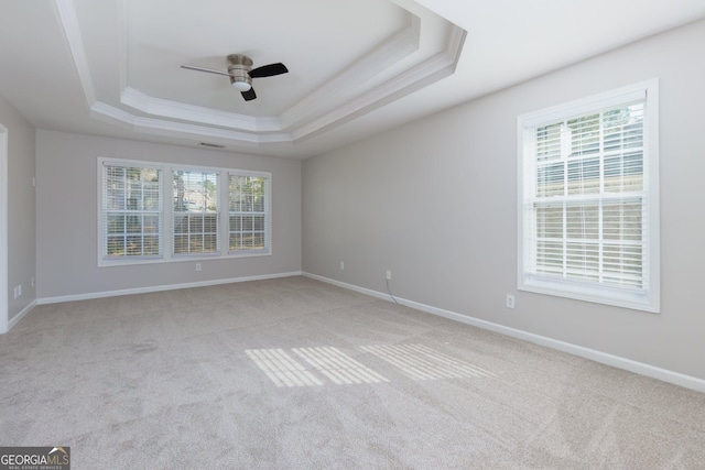 spare room with light carpet, baseboards, a ceiling fan, and a tray ceiling