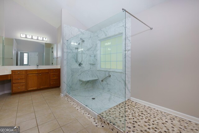 bathroom with vanity, baseboards, a marble finish shower, tile patterned flooring, and vaulted ceiling