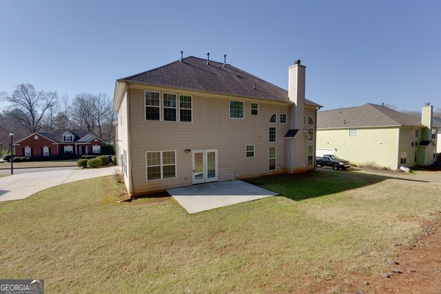 rear view of house featuring a patio, a lawn, french doors, and a chimney