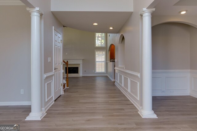 hall with recessed lighting, a wainscoted wall, wood finished floors, and a decorative wall