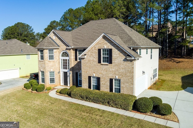 view of front facade with a front lawn, brick siding, driveway, and roof with shingles