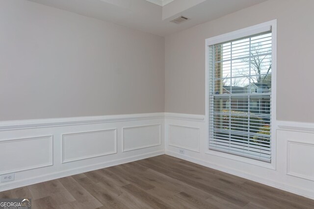 empty room with visible vents, wainscoting, and dark wood-type flooring