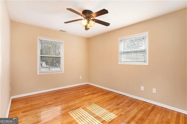 empty room featuring visible vents, baseboards, a ceiling fan, and light wood finished floors