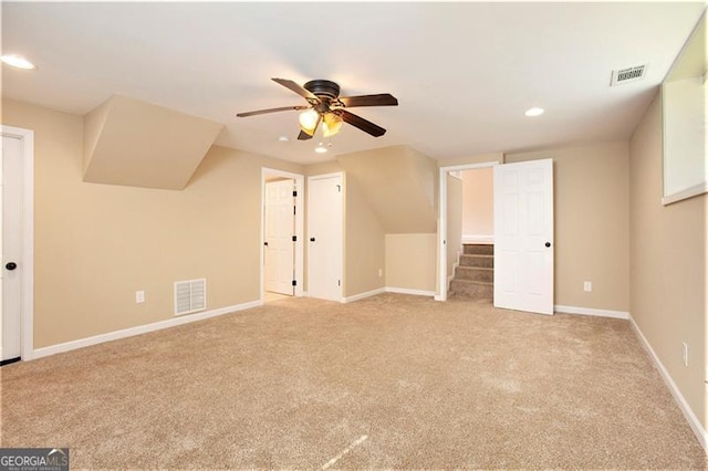 additional living space featuring light carpet, baseboards, visible vents, and ceiling fan