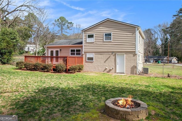 rear view of house featuring a yard, a fire pit, a deck, and fence