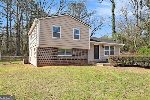tri-level home featuring a front lawn, central air condition unit, fence, and brick siding