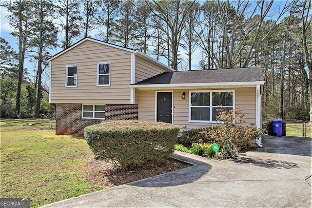 split level home featuring a front lawn, concrete driveway, brick siding, and a shingled roof