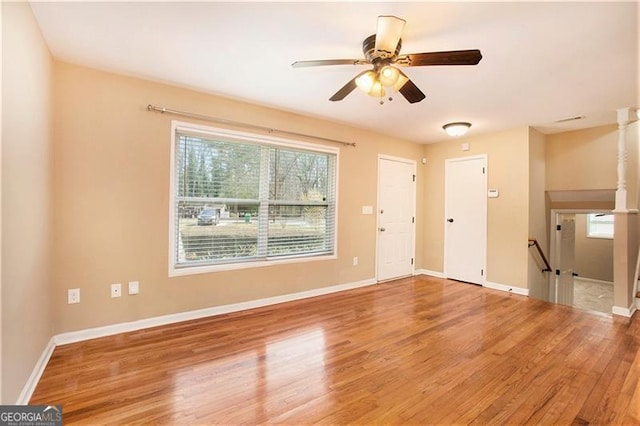 unfurnished living room with wood finished floors, baseboards, and ceiling fan