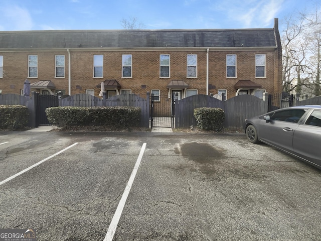 165 N River Dr Unit G, Sandy Springs, GA 30350 - back of property featuring a gate, a fenced front yard, uncovered parking, brick siding, and mansard roof