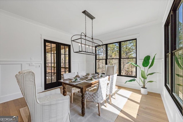 104 Piedmont Cir, Forsyth, GA 31029 - dining room with a chandelier, a decorative wall, ornamental molding, french doors, and light wood-style flooring