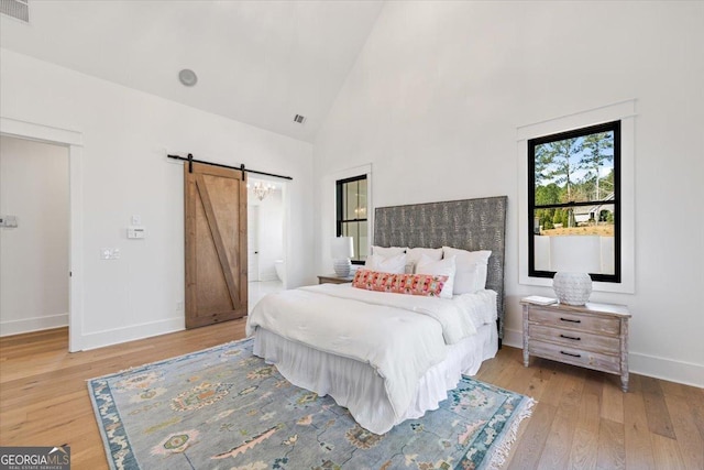 104 Piedmont Cir, Forsyth, GA 31029 - bedroom with a barn door, light wood-style floors, baseboards, high vaulted ceiling, and ensuite bathroom