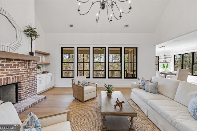 104 Piedmont Cir, Forsyth, GA 31029 - living area featuring a chandelier, high vaulted ceiling, light wood-type flooring, a brick fireplace, and baseboards