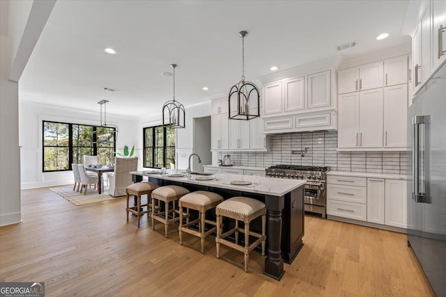 104 Piedmont Cir, Forsyth, GA 31029 - kitchen with high end appliances, backsplash, white cabinets, an island with sink, and recessed lighting