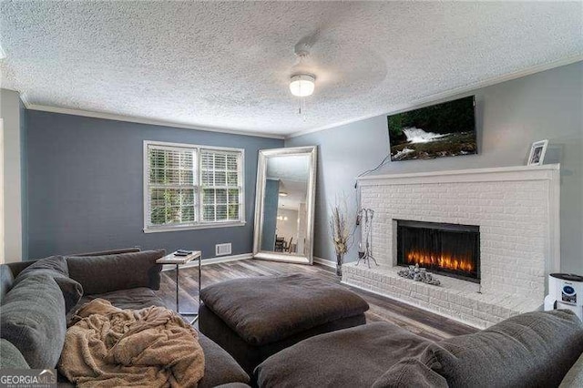 living area with ornamental molding, a brick fireplace, baseboards, and wood finished floors