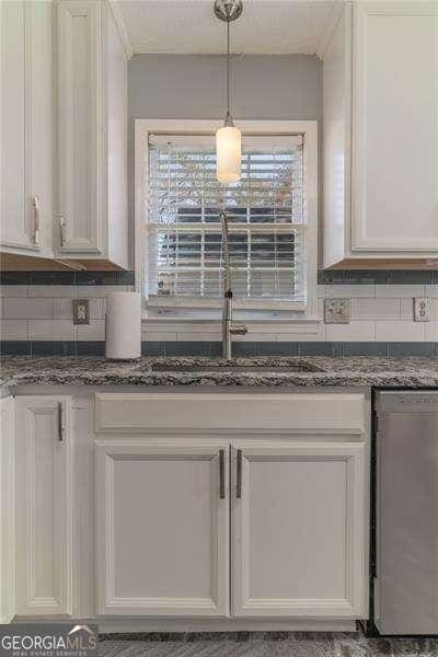 kitchen with pendant lighting, dishwashing machine, dark stone countertops, decorative backsplash, and white cabinetry