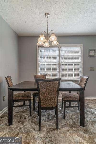 dining area with an inviting chandelier, baseboards, and a textured ceiling