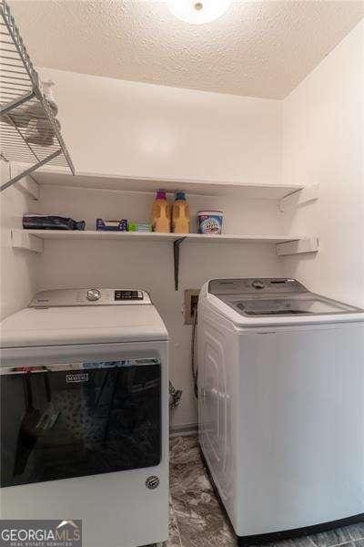 clothes washing area featuring laundry area, separate washer and dryer, and a textured ceiling