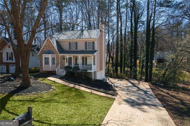 view of front of property featuring covered porch, driveway, a chimney, and a front yard