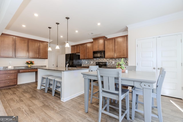 3391 Meadow Grass Dr, Dacula, GA 30019 - kitchen featuring black appliances, backsplash, brown cabinetry, a kitchen bar, and light wood-style floors