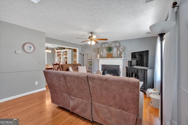 81 Summer Creek Dr, Dallas, GA 30157 - living room featuring baseboards, light wood-type flooring, a fireplace, a textured ceiling, and a ceiling fan