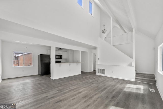 unfurnished living room featuring stairs, visible vents, and wood finished floors