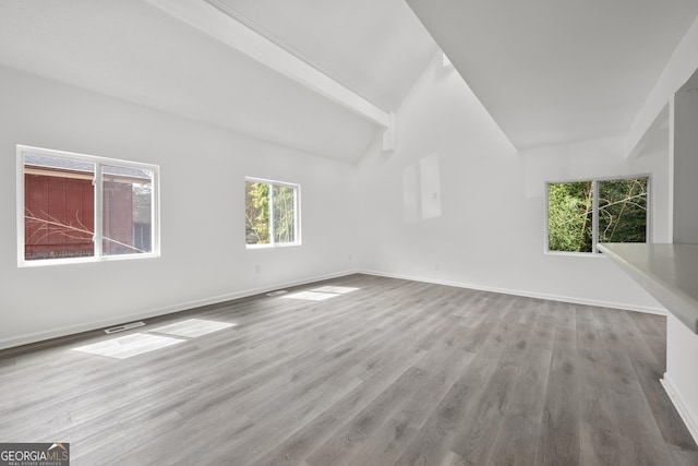 spare room with vaulted ceiling with beams, visible vents, wood finished floors, and baseboards