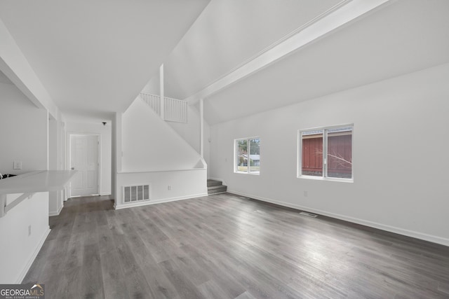 unfurnished living room featuring baseboards, visible vents, wood finished floors, and stairway