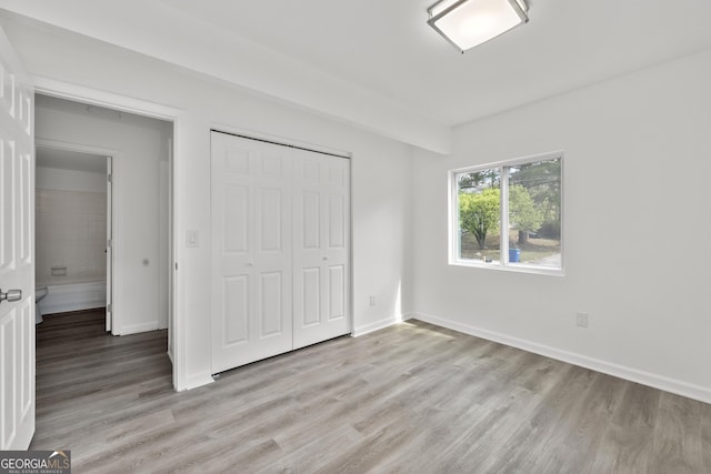unfurnished bedroom featuring a closet, baseboards, and light wood-style floors