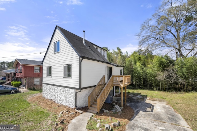 view of property exterior with central air condition unit, stairway, a deck, and a shingled roof