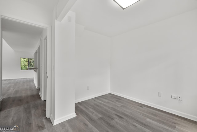 spare room with baseboards and wood finished floors