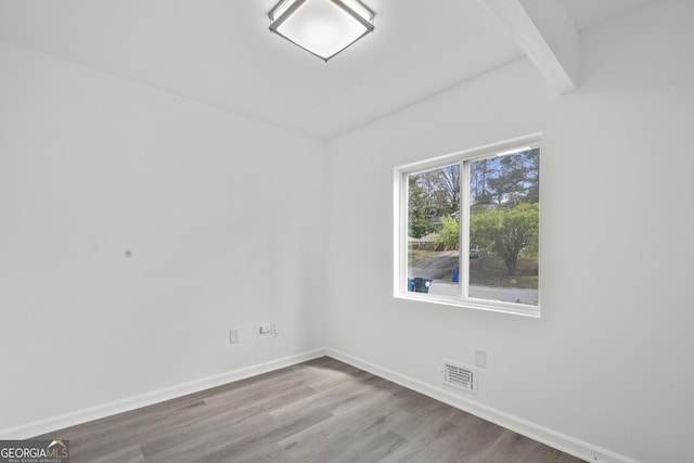 spare room featuring baseboards, visible vents, and wood finished floors
