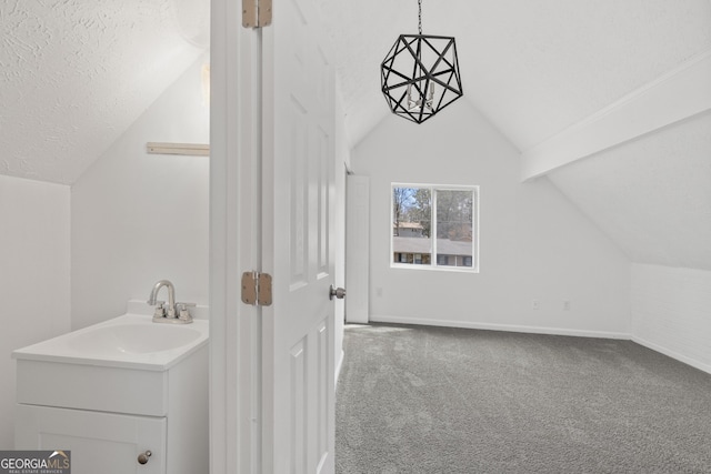 bonus room with a textured ceiling, carpet, baseboards, lofted ceiling, and a sink