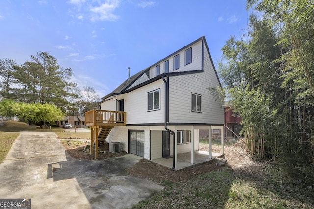 back of property featuring stairs, a deck, driveway, cooling unit, and a patio area