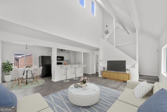 living area with stairs, high vaulted ceiling, and wood finished floors