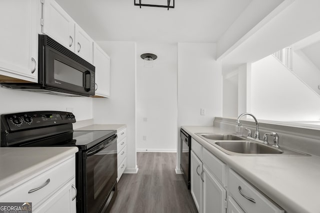 kitchen featuring light countertops, a sink, white cabinets, wood finished floors, and black appliances